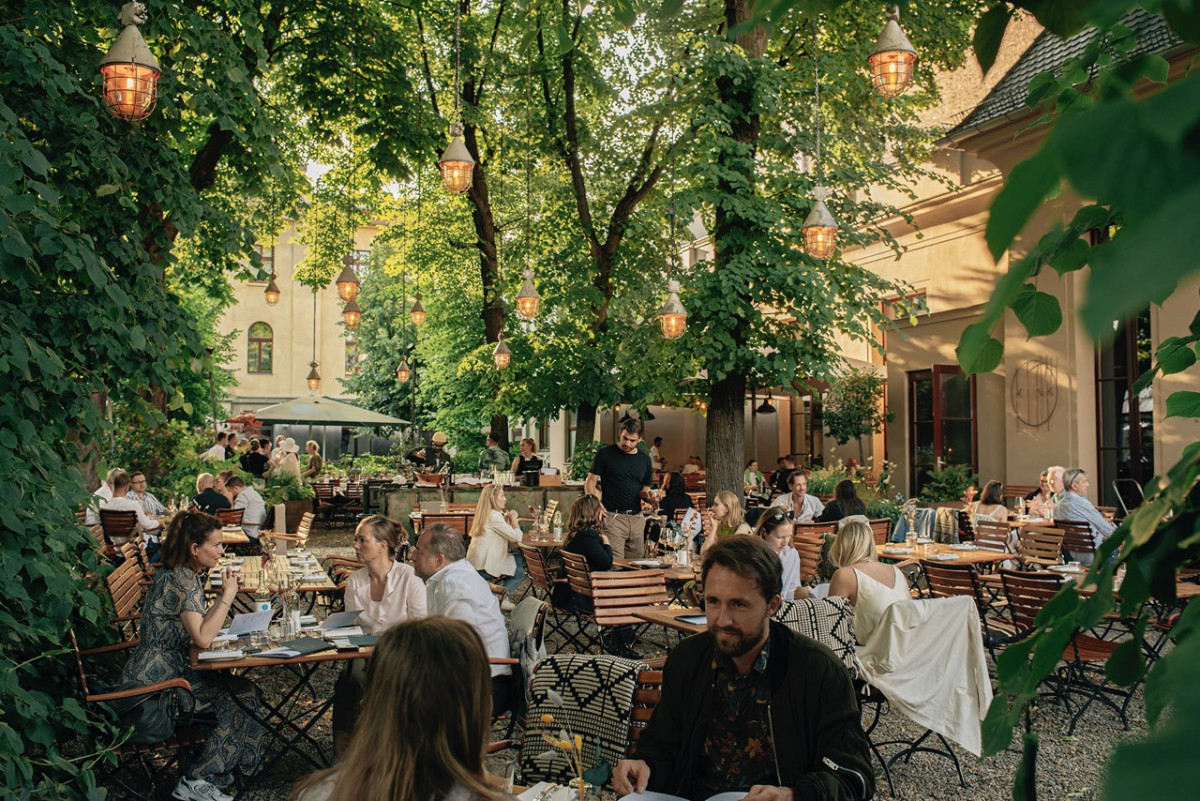 Brunch im grünen Innenhof des KINK Berlin – Gäste genießen Speisen und Drinks auf der Terrasse
